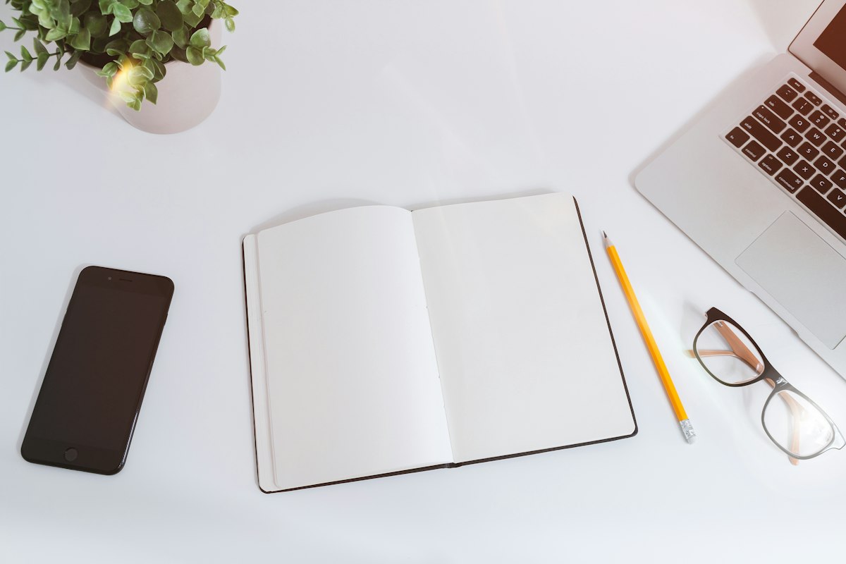 Cuaderno abierto y ordenador sobre una mesa de trabajo